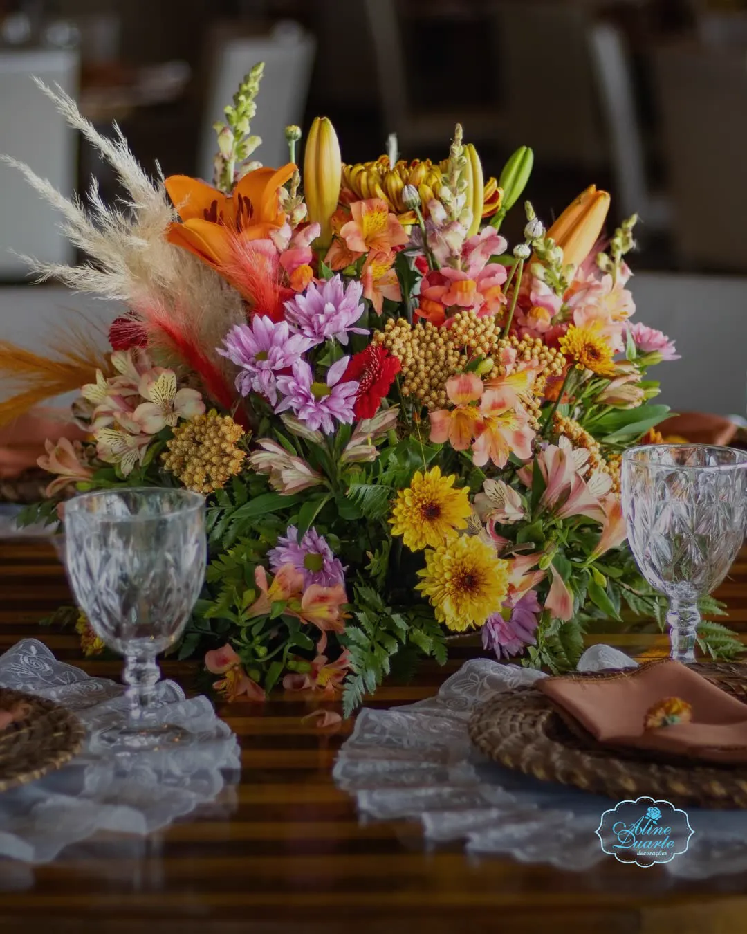 Arranjo de flores coloridas sobre mesa posta com taças de cristal